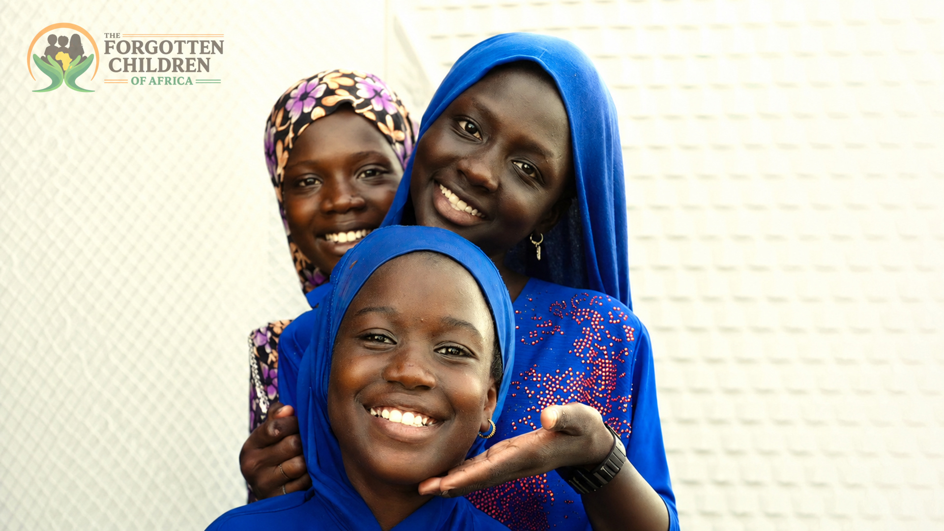 Three smiling girls in blue headscarves
