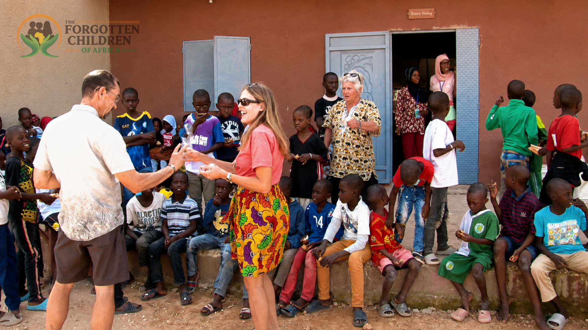 Visitors greeting children outside the school.